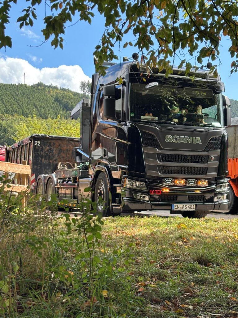 Schwarzer Scania Abroller beim Aufladen eines Contaoners