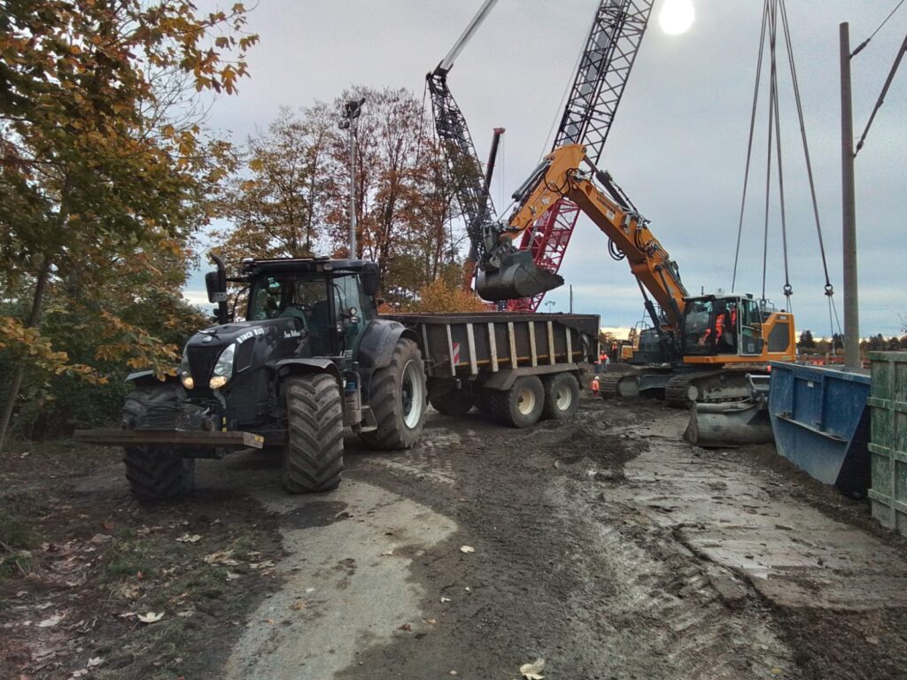 Traktor mit Mulde wird beladen von Bagger auf einer Baustelle